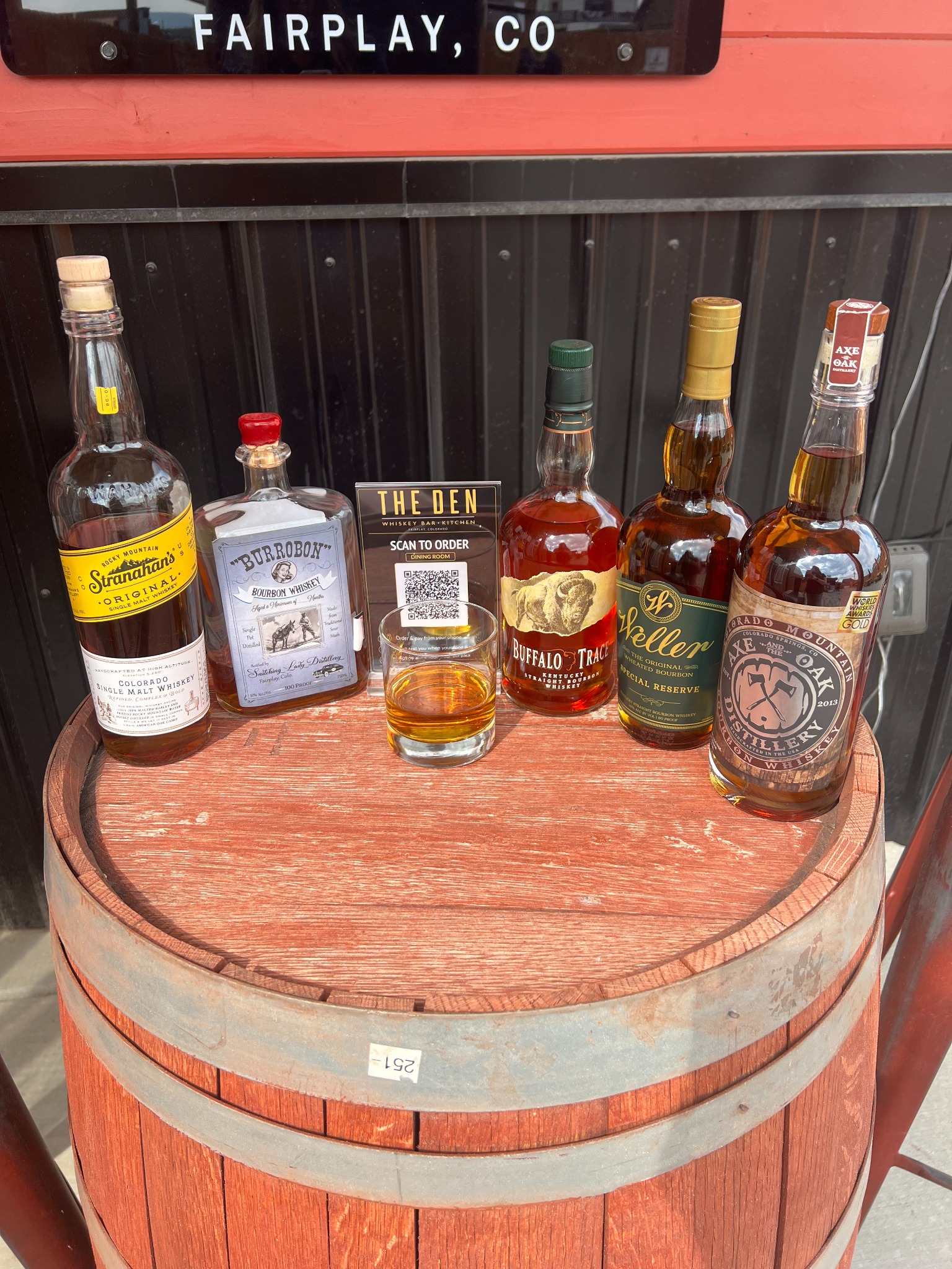 A selection of Colorado and Kentucky whiskeys displayed on a barrel at The Den